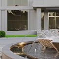 Multi Tiered Water Fountain In Front Of Modern Building With Glass Windows And Green Shrubs