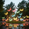 Colorful Butterfly Shaped Landscape Sculpture Illuminated At Night With Surrounding Trees And Reflections In Puddles