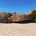 Large Natural Stone Boulders and Wood Tree in Sandy Desert with Clear Blue Sky
