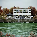 Waterfront Commercial Street with Modern Building Autumn Trees Outdoor Seating and Boats