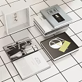 Stacked Books And Open Magazine With Black White Photos Geometric Designs On White Tiled Background