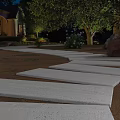 Nighttime Residential Garden Landscape With Curved Stone Walkway Lighting Greenery And Flower Beds