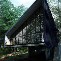 Modern Detached Villa With Large Glass Windows Sloped Roof And Green Tree Surroundings