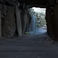 Natural Scenery Of Stone Passage With Tall Stone Walls Dirt Ground And Light At End