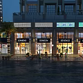 Nighttime Commercial Street With Modern Storefronts Bright Lighting And Wet Pavement