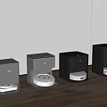 Different Colored Robotic Vacuum Cleaner Docks Arranged On Wooden Floor With White Wall