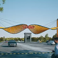 Scenic Modern Entrance Gate With Yellow Curved Design EAGLE Sign And Cars Trees Around
