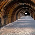 Stone Arch Tunnel Interior With Paved Floor Graffiti Walls And End Light