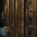 Art Installation With Tall Vertical Golden Paper Structures And Reflective Floor For Visitors