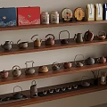 Various Tea Sets And Packages Display On Wooden Shelves With Ceramic Teapots