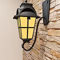 Traditional Black Metal Wall Lantern with Yellow Illuminated Shade on Stone Brick Wall