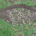 Green Hillside Scenery with Dirt Path Stones and Red Object Under Dark Sky