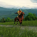 Scenic Green Hills Grassland with Snow Capped Mountains under Cloudy Sky and Rider on Horseback