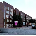 Red Brick School Building with Multiple Floors Windows Campus Road Vehicle and Sign