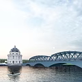 Scenic Steel Arch Bridge Over River With White Domed Building And Small Boat Sunset View