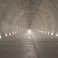 Concrete Elevator Aisle With Arched Ceiling And Side Lighting Leading To Bright End