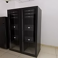 Black Storage Cabinet With Glass Doors And Adjacent Cabinet In White Wall Light Floor Room