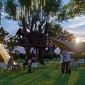 Garden Landscape with Treehouse Illuminated Slide Lawn People Gathering Canopies and Lanterns at Sunset