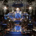 Luxurious Banquet Hall With Blue Stage Crystal Chandeliers Floral Decorations Elegant Lighting And Floor Reflections