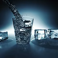 Transparent Glass With Ice Cubes And Cold Water Pouring Into It