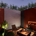 Cozy Courtyard Garden With Brick Wall Wooden Chairs Fire Pit And Lush Greenery