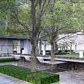 Modern Garden Landscape Featuring Lush Trees Trimmed Hedges Stone Paved Ground And Outdoor Seating