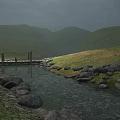 Scenic Natural Stream With Rocks Grass And Wooden Bridge Near Rolling Hills