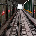 Train Railway Tracks In Industrial Tunnel With Green Pillars Rusty Metal And Red White Stripes