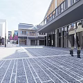Spacious Commercial Street With Brick Buildings Trees And Pedestrians Under Blue Sky
