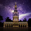 Illuminated Blue Tower With Star Trails And Milky Way In Night Sky Surrounded by Trees