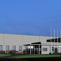 Modern Industrial Factory Building With White Exterior Large Windows Front Lawn And Entrance Area