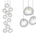 Multiple Transparent Glass Pendant Lights with Irregular Shape Hanging Illuminated in Modern Interior