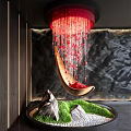 Curved Wood Sculpture With Hanging Red Beads Over Green Plants Stones And Dark Textured Wall