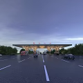 Modern Entrance Gate With Vehicles Passing Through Unique Roof Structure Green Trees And Evening Sky