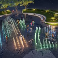 Nighttime Water Fountain With Colorful Lighting And People Playing In Park