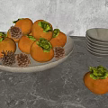 Fresh Persimmons in Brown Plate with Pine Cones Bowls and Clear Cups on Gray Tabletop