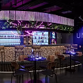 Modern Restaurant Interior With Neon Lights Green Plants Bar Counter And Round Tables