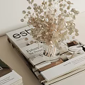 Dried Flowers In Glass Vase With Stacked Design Magazines And Books
