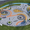 Colorful Circular Children's Playground With Spiral Structure Sandpit Pavement And Trees