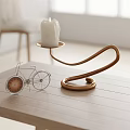 Copper Curved Candle Lamp With White Candle Small Bicycle Model On Light Wooden Tabletop