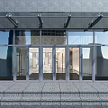 Modern Building Entrance With Glass Doors Stone Facade And Glass Canopy
