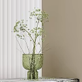 Slender Stemmed Green Leaf Sprigs in Green Textured Vase Against Light Colored Wall Background