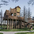 Elevated Wooden Children's Play Area With Tree House Slide Stairs And Grass Surroundings