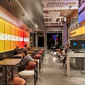Modern Restaurant Interior With Yellow Orange Wall Decor Seating Area And Counter