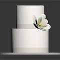 Two Tiered White Cake With White Flower Decoration On Silver Round Tray