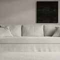 Light Beige Sectional Sofa With Throw Pillows And Black Wall Art On Light Colored Wall