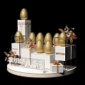 Golden Eggs Display On White Tiered Platform With Decorative Flowers And Gift Boxes