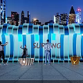 Surfing Themed Illuminated Wave Structure With People Taking Photos In Urban Night View