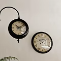 Two Black Decorative Clocks With Roman Numerals On Light Colored Wall