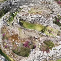 Ancient Stone Ruins With Circular Walls Green Grass And Purple Flowers